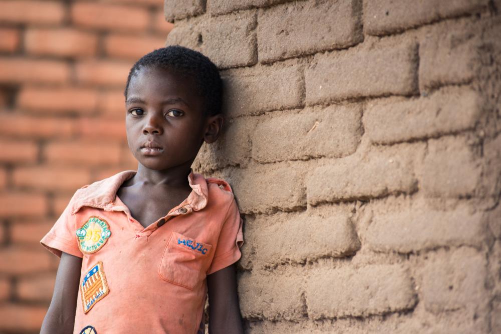 A girl stands in front of a brick wall