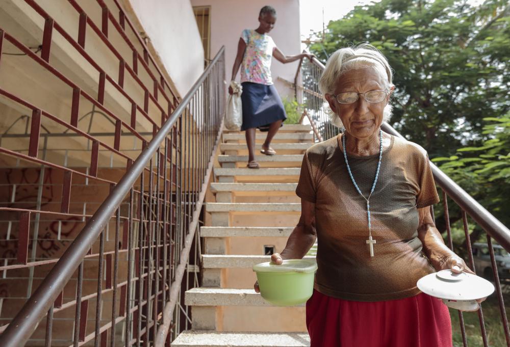 Yolanda Hernández, de 76 años, camina a su casa en La Cumba, Alamar, con comida que le regala el programa "Al Amor de Alamar" casa donde se sirve comida a familias necesitadas en este barrio pobre de La Habana, Cuba.