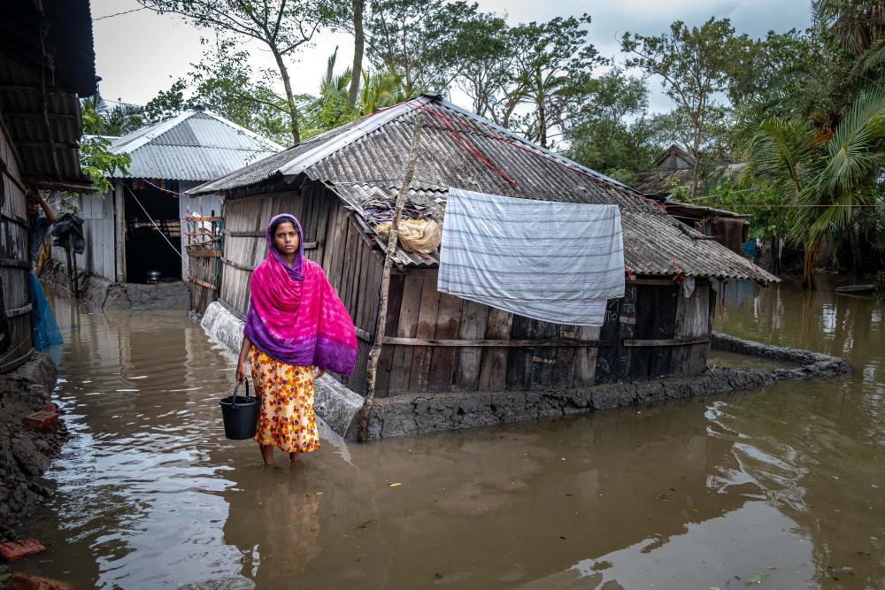 Woman from Bangladesh stands in flooding in front of house