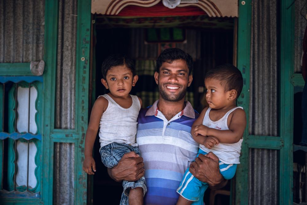 Man from Bangladesh holding his two children