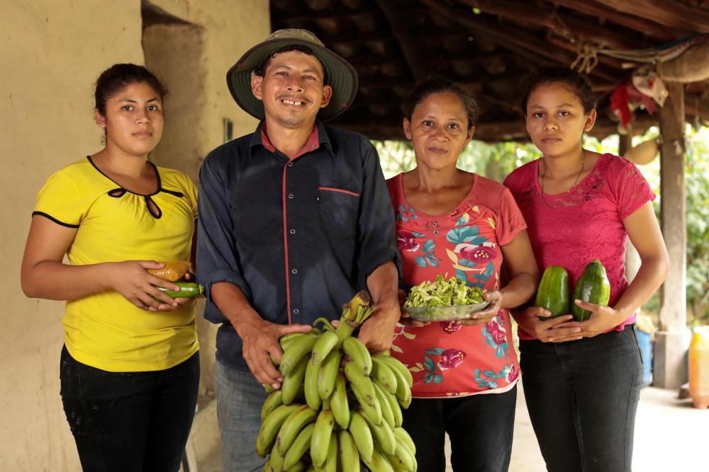 A family from Honduras stands together holding plantains