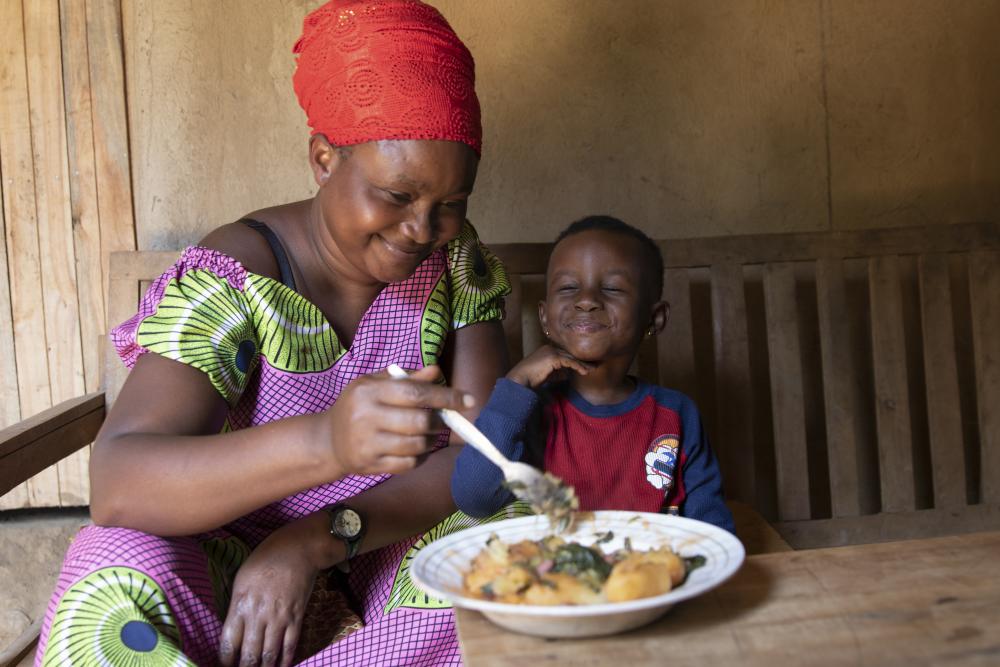 Woman from Rwanda feeds her daughter