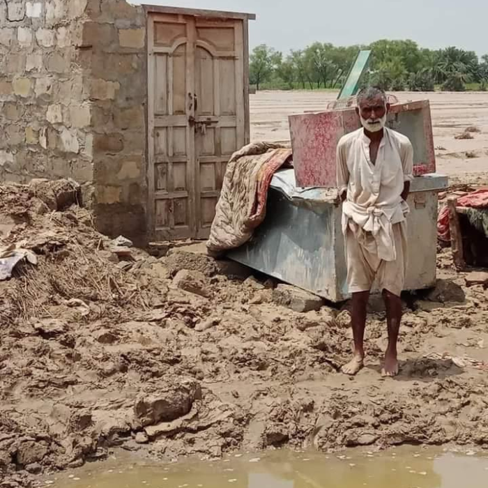 A man standing in the mud outside of a destroyed building