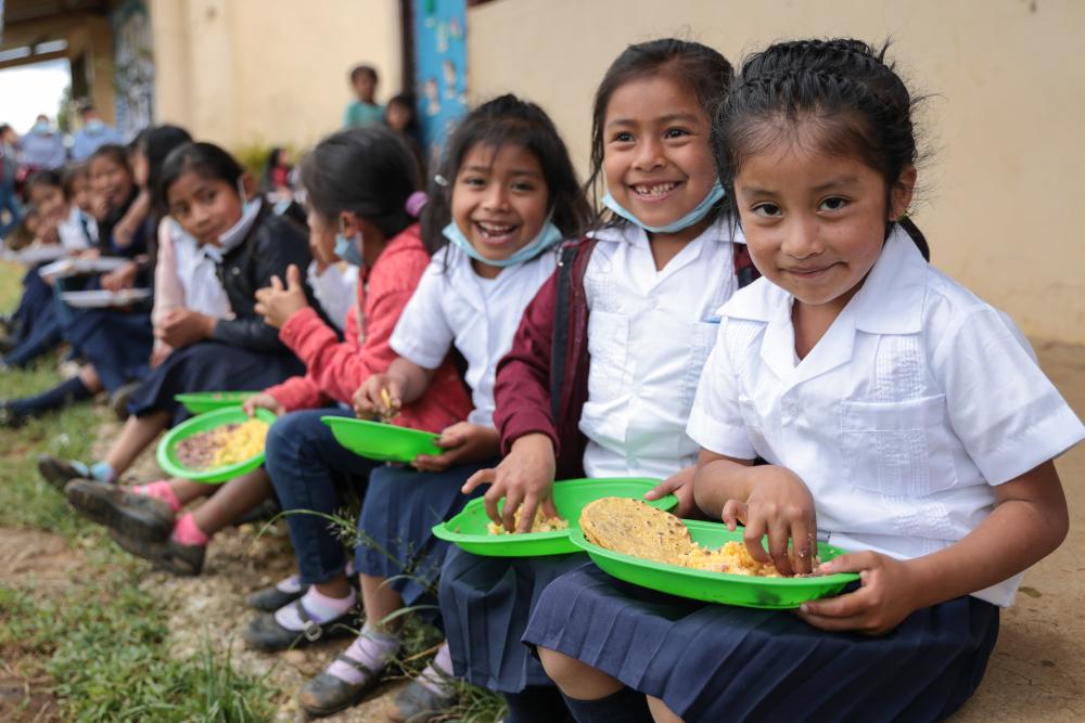 Children sit outside school eating lunch