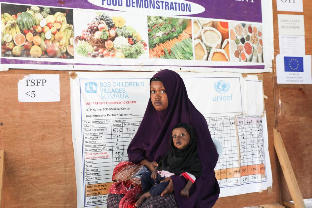 Somalian woman holds her daughter at a health clinic