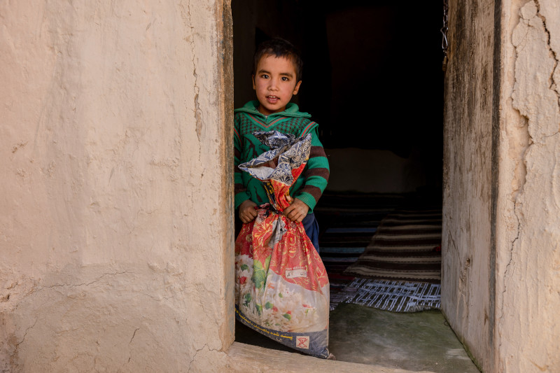 Young boy holding large bag of rice