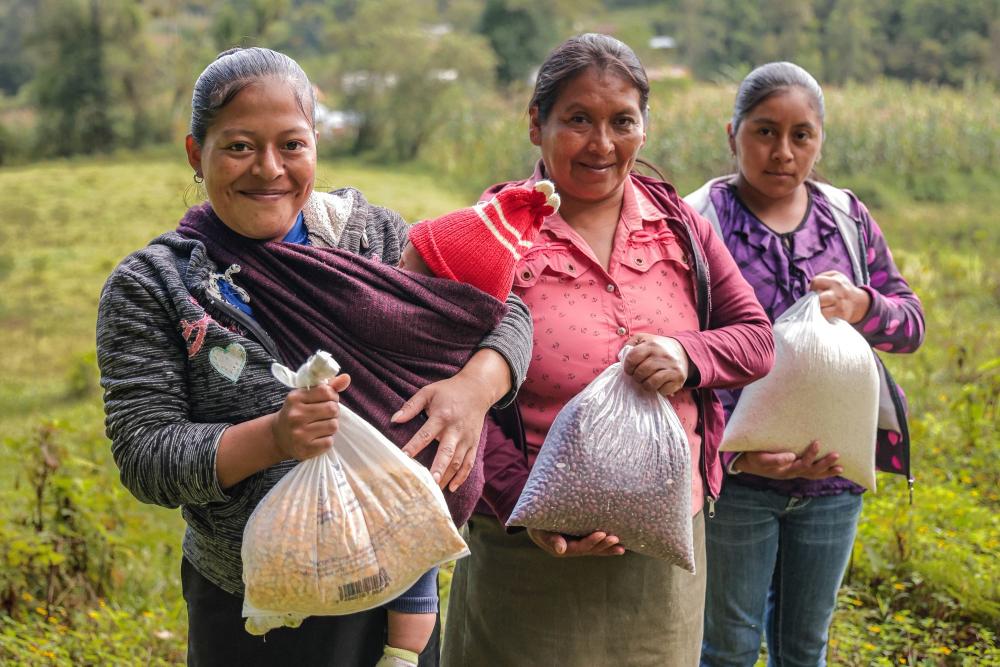 Three Honduran woman pose with bags of food