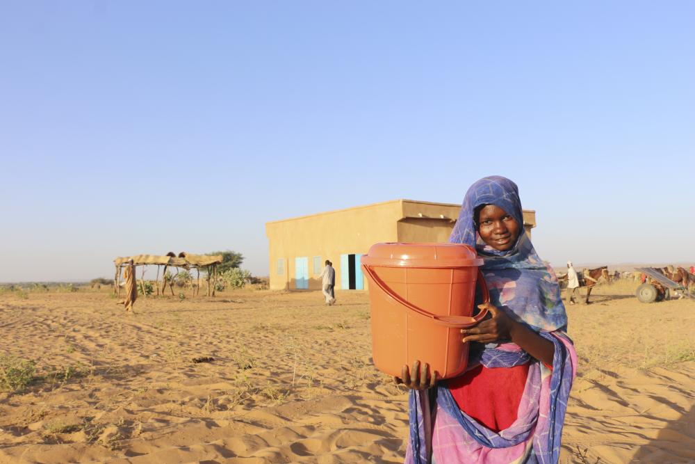 Woman in field holding jug of water