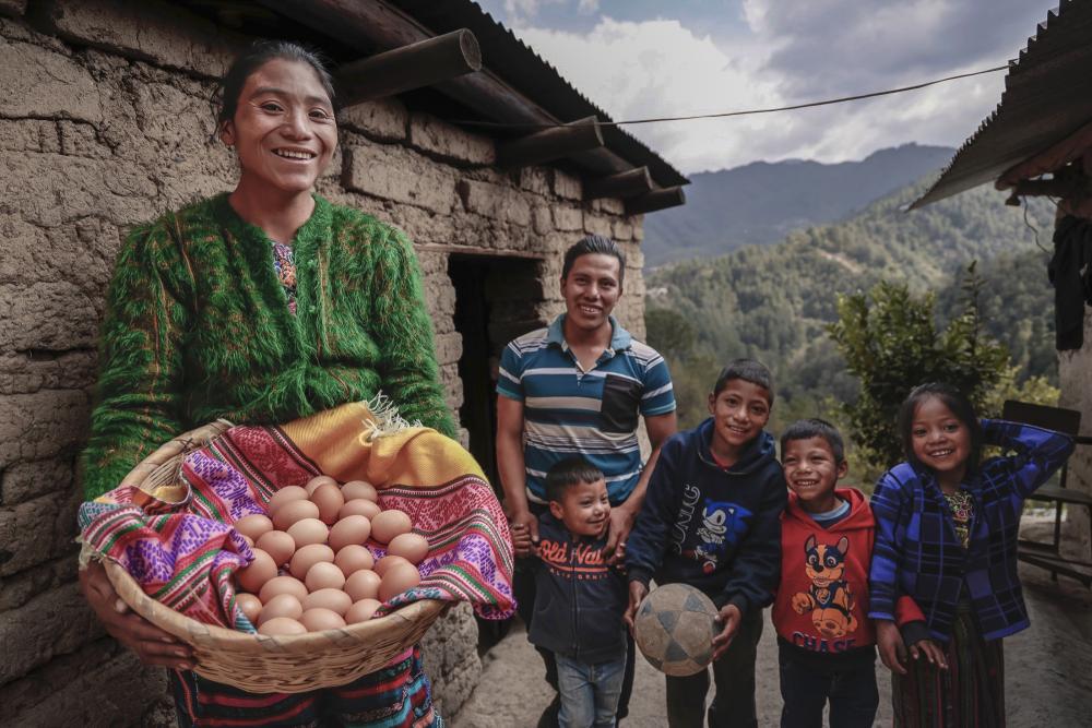Mujer sostiene canasta con huevos frente a su familia