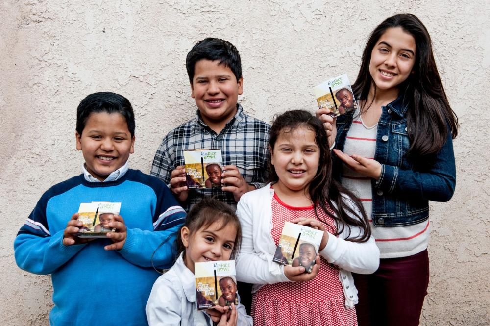 Grupo de niños sosteniendo una pequeña caja de cartón en sus manos. 
