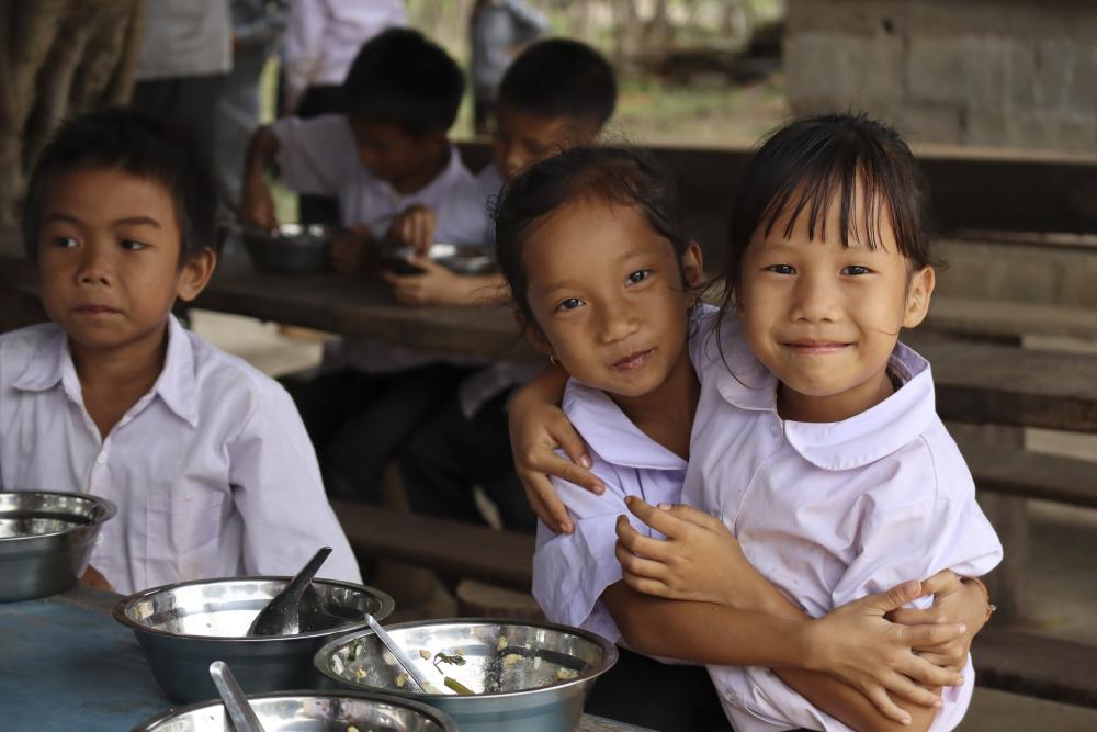 Two students hugging at lunch table