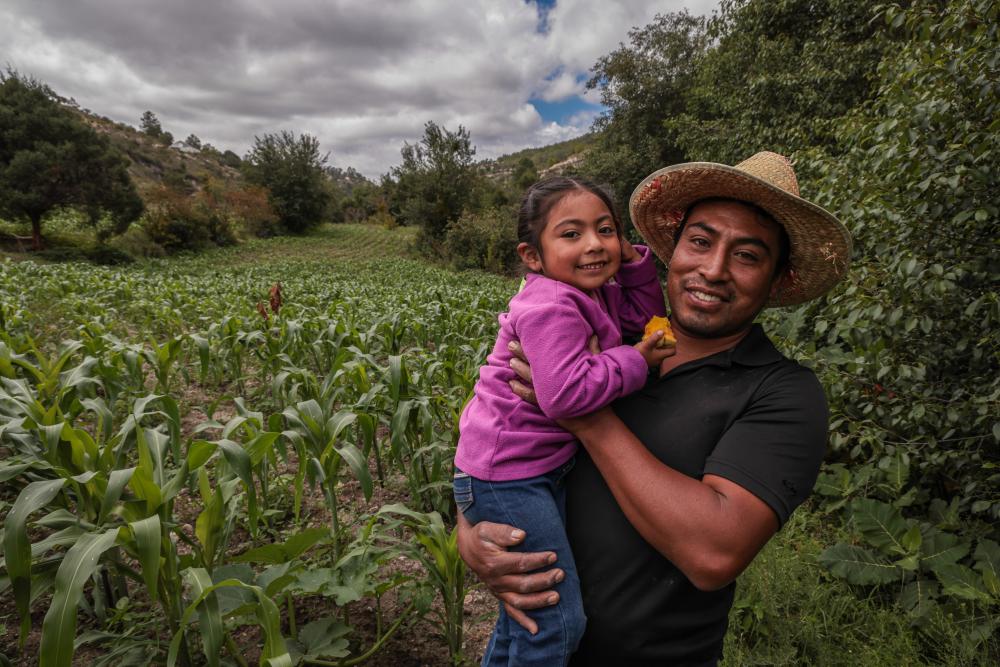 Man holds daughter near farm