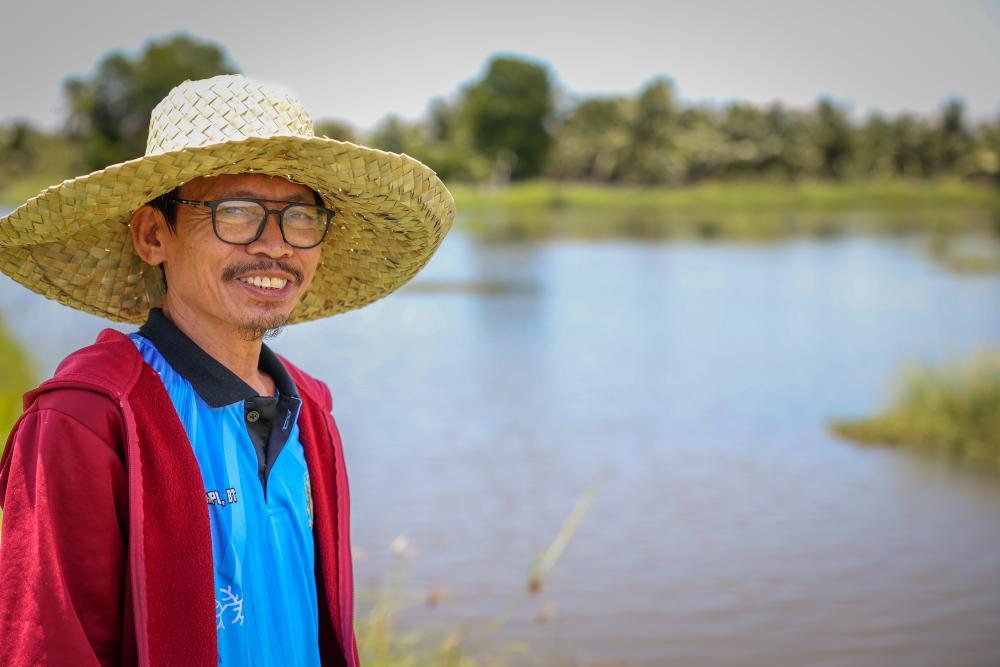 Man stands next to fishpond