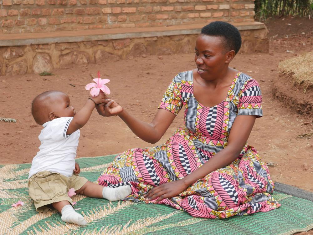 Mother and son on a mat holding a flower