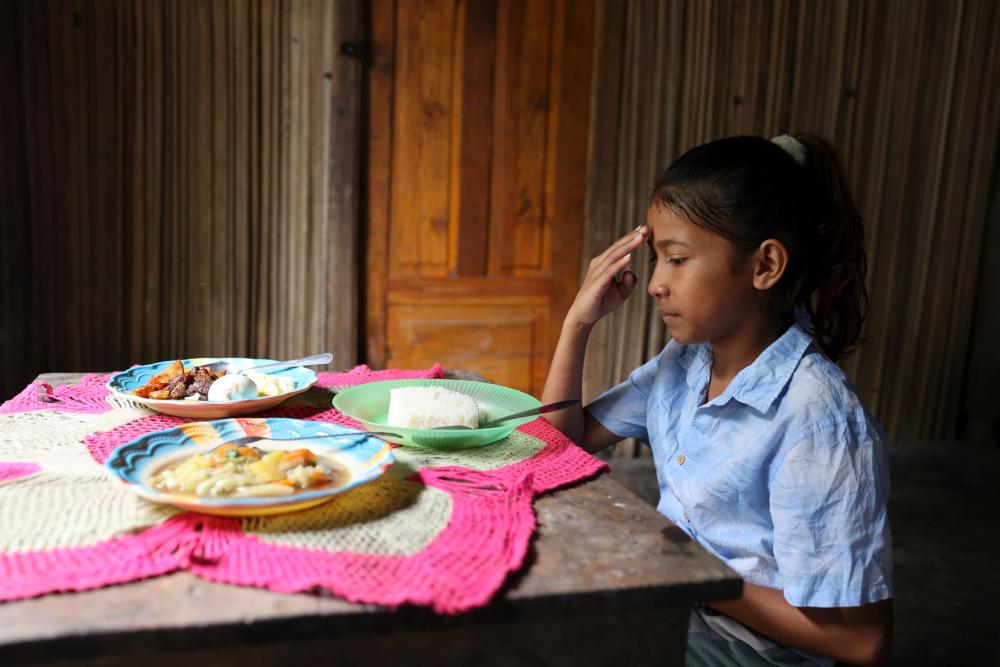 A child sitting at a table with plates of food. 