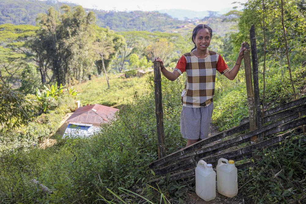Girl standing on hill with two water jugs