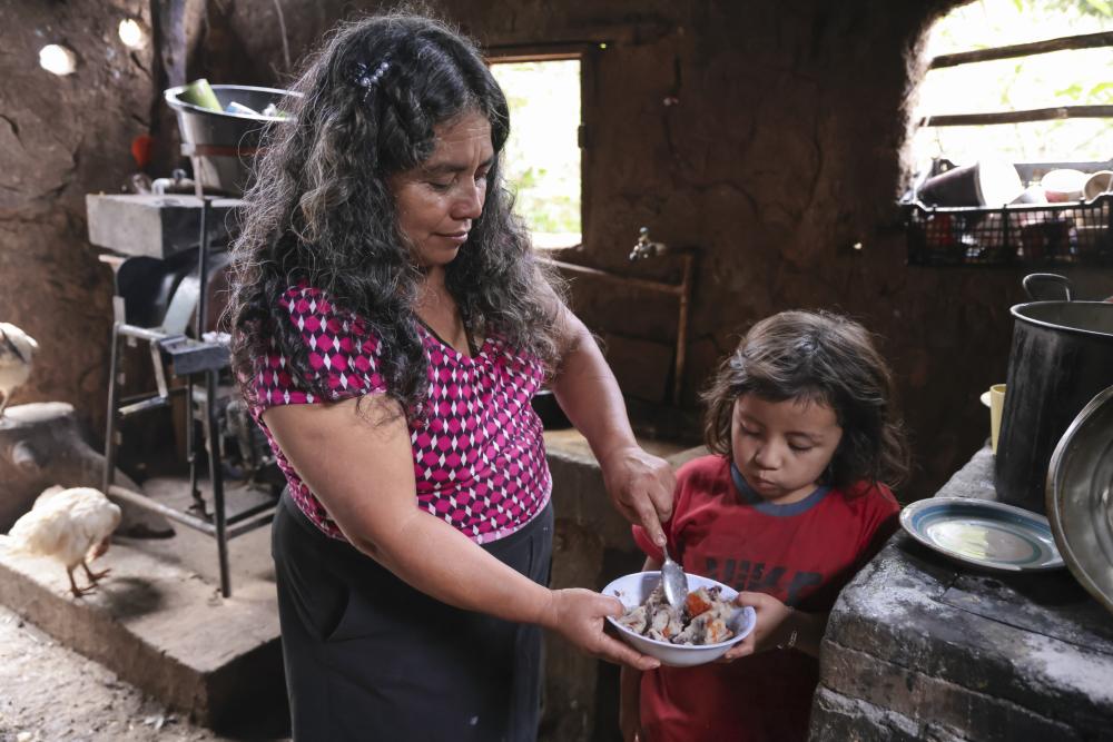 Una madre da un plato de comida a su hija.