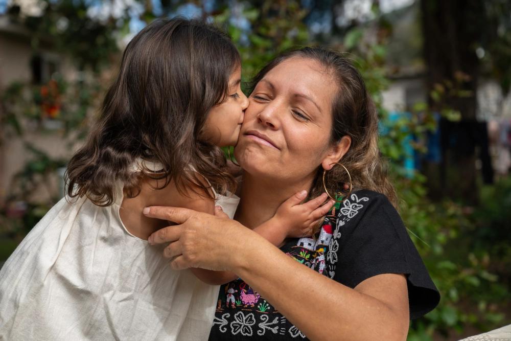 Una niña le da un beso a su mamá